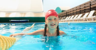 The portrait of happy smiling beautiful teen girl at the swimming pool. Little child at blue wate. Pool, leisure, swimming, summer, recreation, healthy lifstyle concept